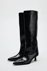 Bota de caña alta color negro de cuero sintético, con punta fina y tacón kitten.