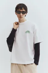 Remera blanca de algodón pesado con cuello redondo y estampado pequeño en el pecho. Corte oversized con hombros caídos y bajo recto.