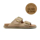 Sandalias bajas de cuero color beige con doble tira y hebillas metálicas doradas.
