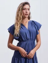 Vestido midi celeste de poliéster, con cuello a la base y escote en V. Presenta cintura con frunces y lazo de ajuste, mangas ranglan con sisa amplia y falda escalonada. Marca Emma & Michele.