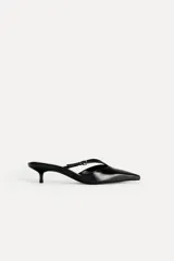 Zapato destalonado tipo mule de cuero negro, con punta fina, tira delantera con hebilla y tacón kitten.