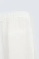 Pantalón blanco de lino con corte relajado (relaxed fit), cintura elástica, bolsillos frontales y un bolsillo trasero de vivo.