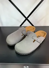 Zuecos grises con plantilla color cuero y hebilla plateada ajustable.