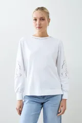 Sweatshirt rojo de manga larga con cuello redondo y calados bordados en los hombros y mangas.