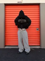 Pantalón de jogging gris con corte amplio y logo bordado en el muslo.