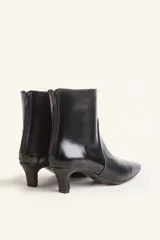 Bota corta de cuero vacuno con estampado animal print serpiente en tonos blanco y negro, con puntera fina y cierre trasero. Tiene taco chupete y suela de cuero.