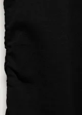 Vestido midi negro de punto, con corte ajustado, cuello redondo y mangas largas. Presenta un frunce lateral en la falda.