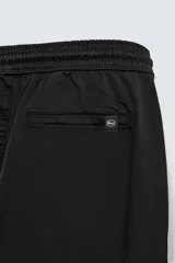 Pantalón jogger negro de corte slim fit, confeccionado en tejido de algodón con cintura elástica ajustable con cordón, bolsillos frontales y traseros de vivo, y bajo con puño elástico.