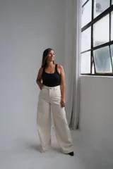 Jean de corte wide leg en color crudo, con tiro alto y costuras reforzadas en contraste. Presenta diseño de cinco bolsillos y cierre frontal con botón metálico.