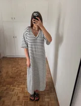 Vestido midi de punto con rayas horizontales blancas y negras, escote en V y mangas cortas. Presenta tajos laterales.