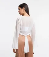 Blusa cropped de chiffon color blanco, con escote en V cruzado, mangas largas acampanadas y lazo en la espalda.