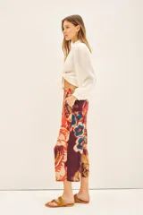 Pantalón capri con estampado floral en tonos naranja, rojo, azul y marrón. Tiene corte regular, bolsillos laterales y elástico en la parte trasera de la cintura.