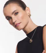 Conjunto de bijouterie de metal dorado, compuesto por caravanas de aro y collar con colgante de aros entrelazados.