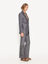 Blazer confeccionado en lino con apariencia denim, con solapa y cuello con flecos. Cierre con botones plateados y forro de tafeta jacquard.