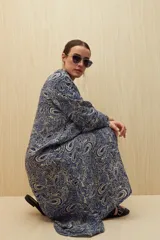 Vestido camisero midi color marrón con estampado de flores rosas, cinturón marrón y mangas largas.