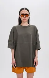 Remera de manga corta color verde militar, con calce extra oversize y un recorte horizontal que atraviesa el pecho y la espalda.