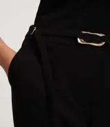 Pantalón de vestir color crudo, de corte recto, con bolsillos laterales y traseros. Se ajusta a la cintura con cinturón de cuero marrón con hebilla dorada.