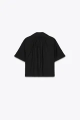 Camisa negra de manga corta con cuello solapa y escote pico. Detalle de nido de abeja en la espalda y cierre frontal con botones.
