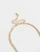 Collar corto dorado de doble cadena, una de eslabones grandes y otra con perlas. Incluye dijes colgantes de bota de cowboy con strass, rosa esmaltada y corona.