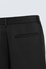 Pantalón de vestir color blanco hueso, de corte recto y tiro medio, con cintura elástica y cierre frontal de botón y cremallera. Presenta bolsillos frontales y bolsillos traseros de vivo.