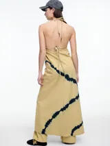 Vestido largo de algodón color beige con estampado tie-dye azul. Tiene breteles finos, escote en V y espalda descubierta.