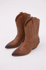 Bota texana color marrón con detalles de tachas y punta afilada.