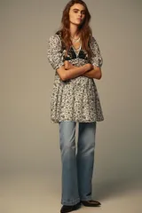 Vestido corto con estampado floral en blanco y negro, escote pico, mangas cortas abullonadas y detalle de chaleco negro con bordados y falsos botones delanteros. Incluye forro interior.