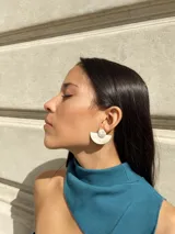 Aros colgantes con forma geométrica, hechos con guampa y detalles metálicos dorados o plateados.