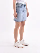 Minifalda blanca de denim con corte evasé y ruedo desflecado.