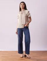 Blusa color beige de gasa con cuello fruncido, escote en V con lazo y mangas cortas con volados.