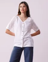 Blusa blanca de algodón con escote en V, abertura con botones y mangas cortas con detalle de broderie.