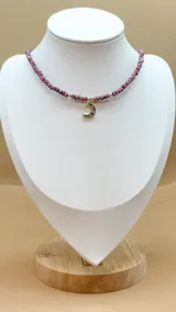 Collar de cinco hilos de cuentas facetadas de jade de Malasia color borgoña, con cuentas doradas y dijes colgantes dorados con incrustaciones de strass: estrella, espiral, mano de Fátima, luna creciente y esqueleto de pez.