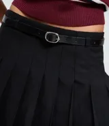 Short pollera negro de sastrería con pliegues estructurados, cintura con trabillas y cinturón ajustable con hebilla redonda.