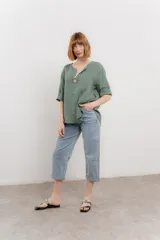 Blusa celeste de lino, con escote en V, manga tres cuartos y botón de madera.