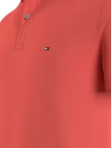Chomba Tommy Hilfiger de corte slim, color salmón, con cuello clásico, cartera de dos botones y logo de la marca bordado en el pecho.