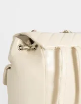 Mochila negra de cuerina acolchada con diseño de líneas diagonales. Tiene solapa con broche decorativo y botón para cerrar. Cuenta con correas regulables, manija superior de material principal y metal, y tira de ajuste de metal.