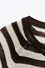 Jersey de punto color verde oliva, con cuello redondo y manga larga. Tiene bajo con aberturas laterales y acabados en rib.