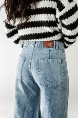 Pantalón de jean celeste con lavado ácido, corte wide leg, tiro medio, godets y ruedo desflecado.