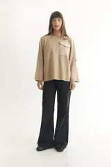 Sweater negro de tejido suave y liviano, con corte holgado, mangas 3/4 con botón decorativo y bolsillo de parche en el pecho.