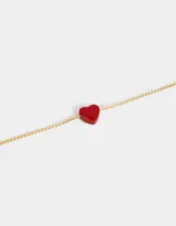 Pulsera dorada de cadena fina con dije de corazón rojo.