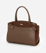 Cartera satchel mediana color marrón, confeccionada en cuero sintético con detalles en gamuza. Cuenta con asas medianas, cierre de cremallera y detalles metálicos dorados. Incluye correa extraíble y regulable.
