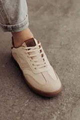 Zapatillas bajas de cuero color marrón con suela de goma color caramelo y cordones marrones.