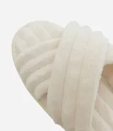 Pantuflas tipo ojota de color blanco hueso, con textura peluda y tiras cruzadas en la parte superior.