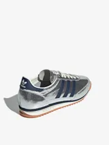 Zapatillas Adidas SL 72 plateadas con detalles en azul marino, suela de goma marrón y cordones blancos.