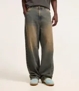 Pantalón super baggy de jeans con lavado dirty en tonos tierra, cintura con trabilla, cierre tradicional, bolsillos y bordado en el bolsillo trasero.