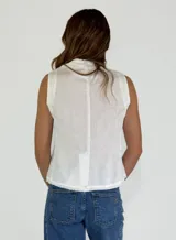 Chaleco beige de lino con escote en V, cierre frontal con botones y terminaciones desflecadas.