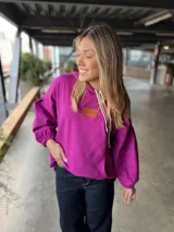 Canguro fucsia con capucha, bolsillo delantero tipo canguro y mangas largas con puños elásticos.