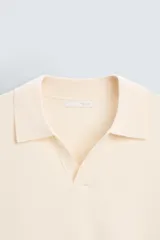 Polo color crema de punto, corte regular fit, con cuello solapa y abertura frontal.