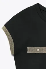 Camiseta negra de corte slim fit, cuello redondo y manga corta. Presenta falsos bolsillos en el delantero y detalle de hilo metalizado en mangas y bolsillos.