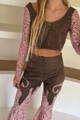 Pantalón oxford de tiro alto, confeccionado en cuero marrón con apliques de encaje floral rosado.